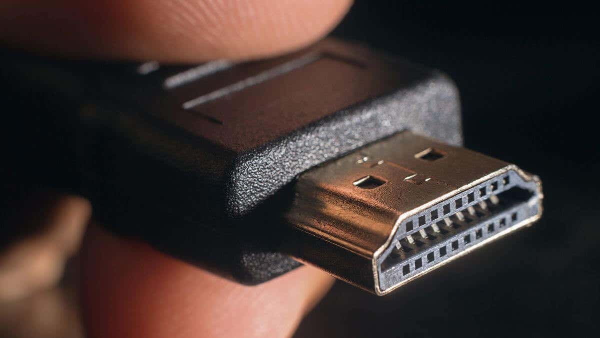 Close-up of an HDMI cable connector held between fingers, showcasing image.