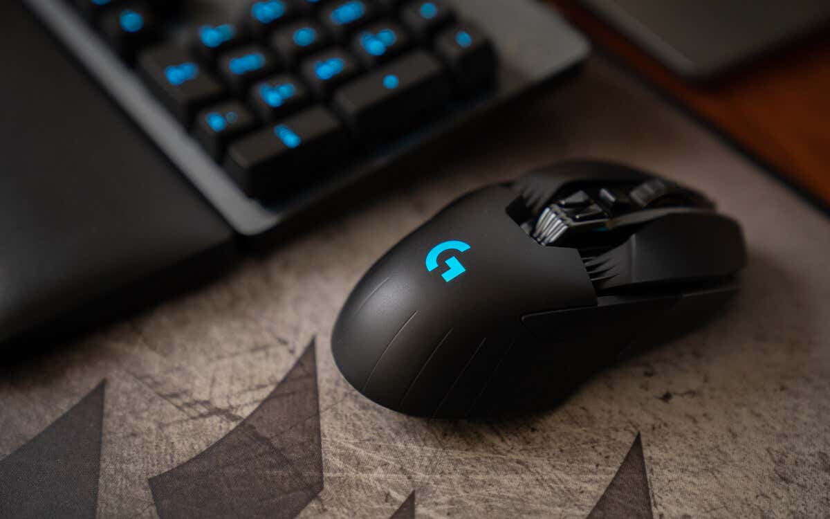 A black gaming mouse with blue lighting, placed on a textured surface next to a keyboard, showcasing image.